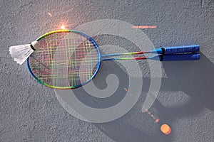 Two colored badminton rackets and a badminton shuttlecock.