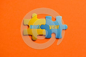 Two colored details of puzzle with text Next year on orange background, Yellow and Blue, close up