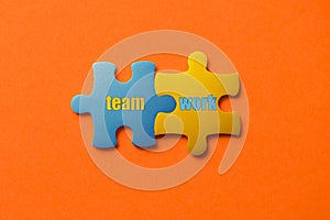Two colored details of puzzle with text Team Work on orange background, Yellow and Blue, close up