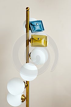 Two colored leather wallets placed on a lamp indoors
