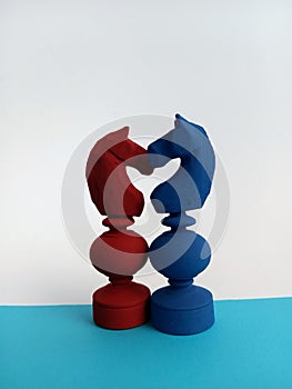 Two colorful Abstract chess pieces cuddling each other on a blue and white background for the concept of love