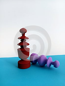 Two colorful Abstract chess pieces one laying on its side defeated on a blue and white background