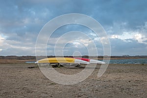 Two colorful canoes on the empty shore of a lake