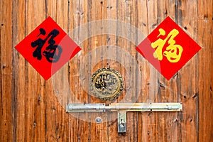 Two colorful Chinese blessing Fu on the  traditional chinese  wooden door with handle and padlock.