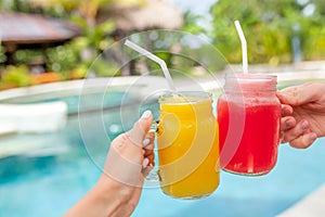 Two colorful fruit shakes in hands. Summer and tropical mood. Cold blended drinks, mango and watermelon fruit smoothie