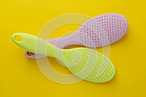 Two colorful hairbrushes on bright yellow
