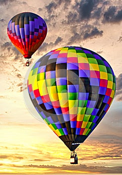 Two colorful hot air balloons ascending into a beautiful sky at sunrise