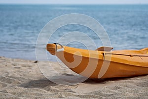 Two colorful orange kayaks on a sandy beach ready for paddlers in sunny day. Several orange recreational boats on the