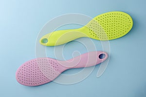 Two colorful plastic hairbrushes on pastel blue