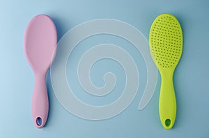 Two colorful plastic hairbrushes on pastel blue