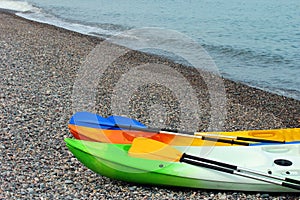 Two colorful sea kayaks with paddles on stony beach