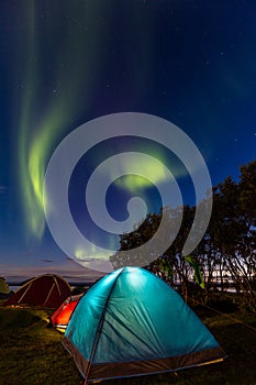 Two colorful sleeping tents under a night sky with green northern lights