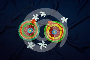 Two colorful terracotta oil lamp or diya with crepe jasmine on blue cloth background