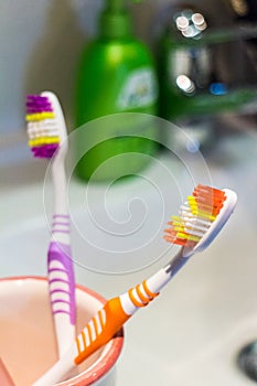 Two colorful toothbrushes in a mug