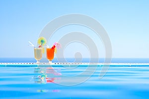 Two Colorful Tropical Cocktails near the Swimming Pool on Background of Warm Blue Sea. Exotic Summer Vacation.