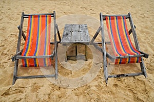 Two colorful wooden lounge chairs on sand beach