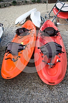 Two Colourful Dual Seater Sit on Top Sea Kayak Parked on Coarse Sand. Watersport Outdoor Adventure Ideas. Equipments fo