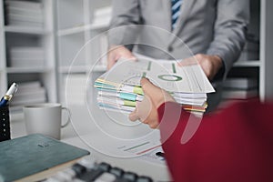 Two company employees handing over papers to each other, marketing staff handing over marketing analysis papers to department