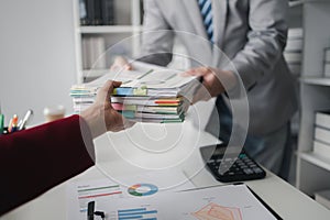 Two company employees handing over papers to each other, marketing staff handing over marketing analysis papers to department