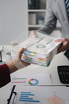 Two company employees handing over papers to each other, marketing staff handing over marketing analysis papers to department