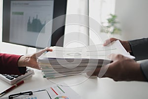 Two company employees handing over papers to each other, marketing staff handing over marketing analysis papers to department