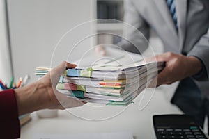 Two company employees handing over papers to each other, marketing staff handing over marketing analysis papers to department