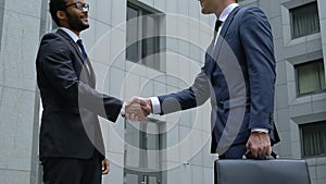 Two company workers in formal suits shaking hands, colleagues greeting, merger