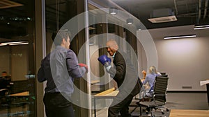 Two Competitive businessmen fighting with boxing gloves in corporate office