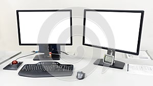 Two computer monitors are on the table in the office. On the monitors white screen to insert images or text