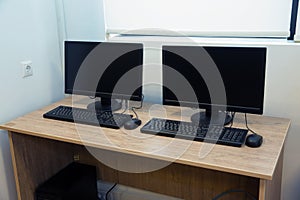 Two computers and a desk . Keyboard and mouse . Two computer monitors with a black screen on a desk