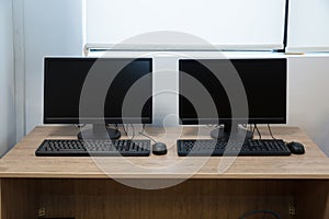 Two computers and a desk . Keyboard and mouse . Two computer monitors with a black screen on a desk