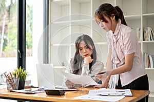 Two concentrated Asian businesswomen are discussing work, analyzing sales data