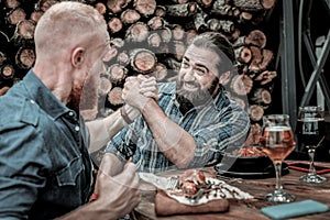 Two concentrated mature men competing in arm-wrestling.