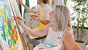 Two confident artists, man and woman, enjoy drawing together with smiles in indoor art studio, while learning and painting