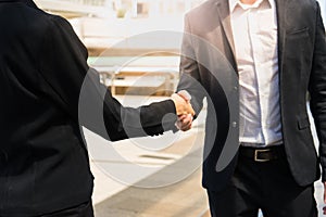 Two confident business man shaking hands for demonstrating their agreement to sign agreement or contract between their commpany