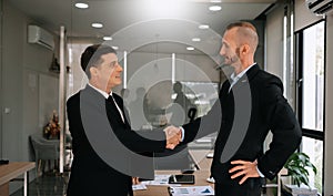 Two confident business man shaking hands during a meeting in the office, success, dealing, greeting and partner