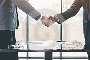 Two confident business men, African American and Caucasian shaking hands during a meeting in the office, success