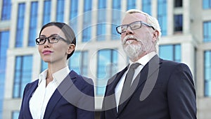 Two confident business partners standing outdoors office center, experience