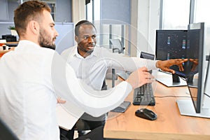 Two confident businessmen, financial analysts or investment advisers sitting at office desk