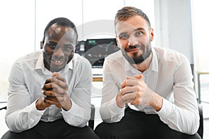 Two confident businessmen, financial analysts or investment advisers sitting at office desk