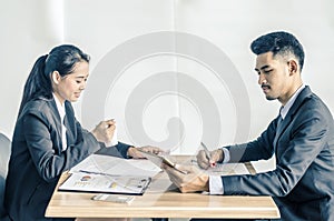 Two confident businesspeople using a digital tablet together while working at a table