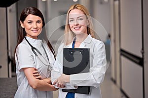 Two Confident Caucasian Female Doctors Posing At Camera In Hospital Hall