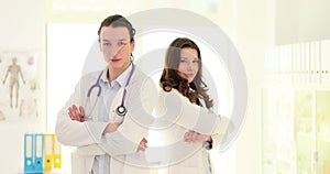 Two confident doctors stand with crossed arms in a hospital room