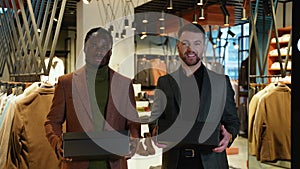 Two confident men with shoe boxes in clothing store