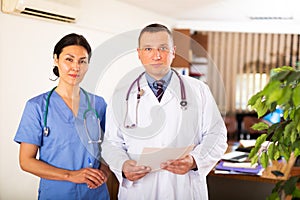 Two confident professional fellow doctors standing in office