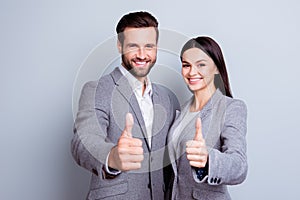 Two confident smiling businesspeople in formalwear showing thumb