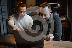 Two confident young businessmen working at laptop