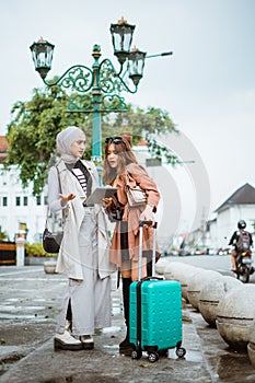 two confuse travellers looking at the tablet while standing at the sidewalk