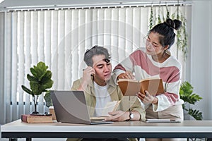 Two confused and thoughtful young Asian college friends are looking at a laptop screen with a serious face and don't