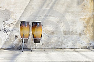 Two congas in front of a vintage wall